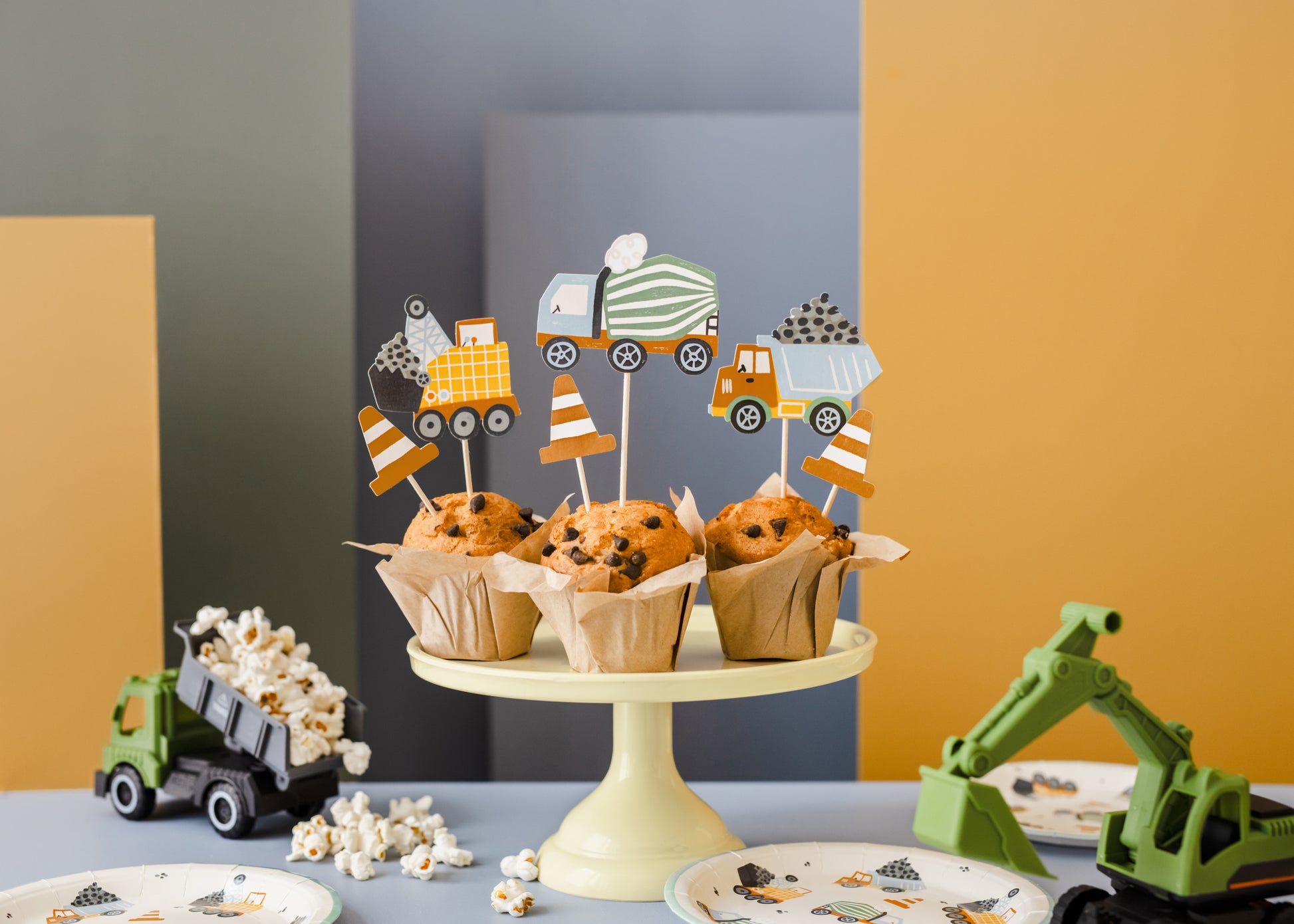 Cupcakes on a stand with construction-themed cupcake toppers against a colorful background