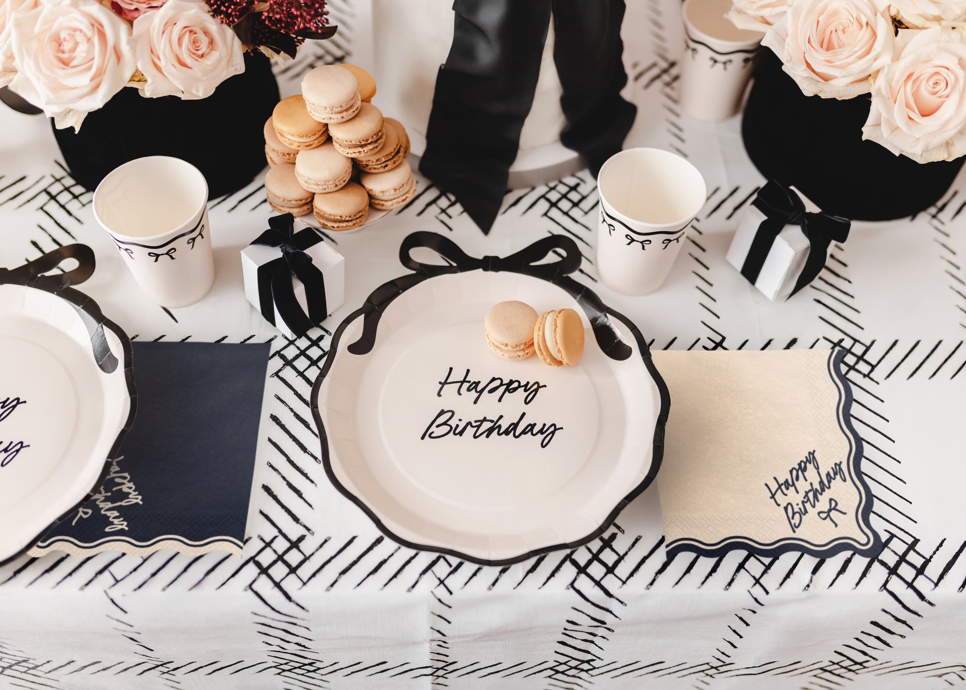 Birthday table setup with beige Happy Birthday bow napkins and black and white decor available at our Toronto party shop