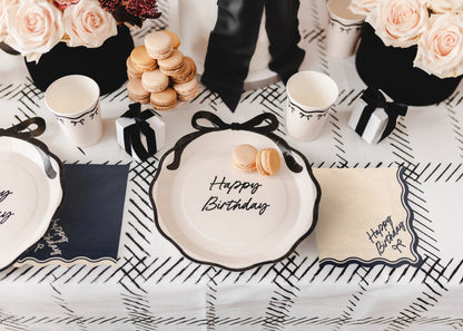 Birthday table setup with beige Happy Birthday bow napkins and black and white decor available at our Toronto party shop