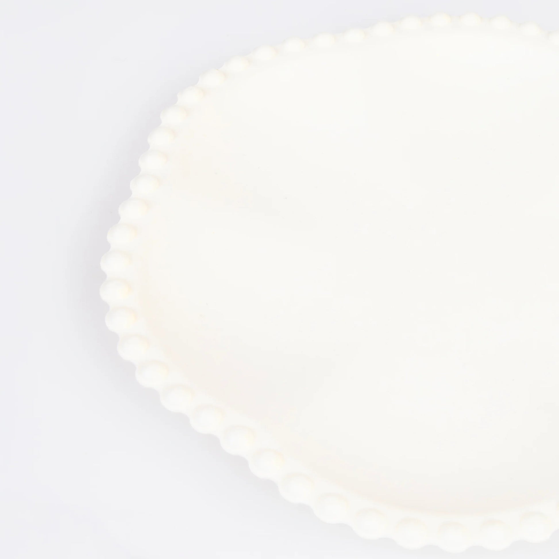 Close-up of cream scalloped paper plate with beaded edge detail