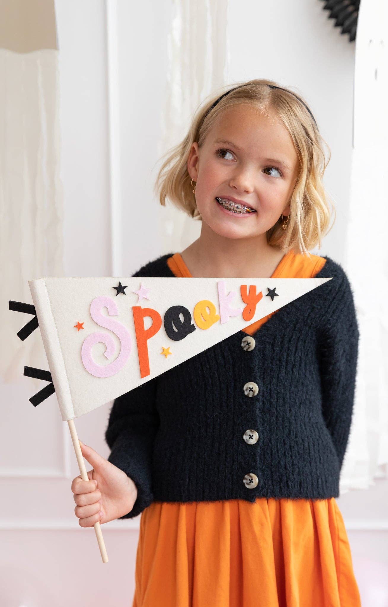 Girl holding spooky felt pennant flag in festive colours, available at our Toronto party shop.
