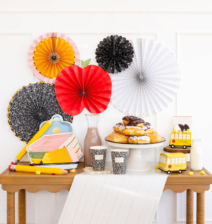 Decorative setup with colorful paper fans, donuts, and a cake on a table.
