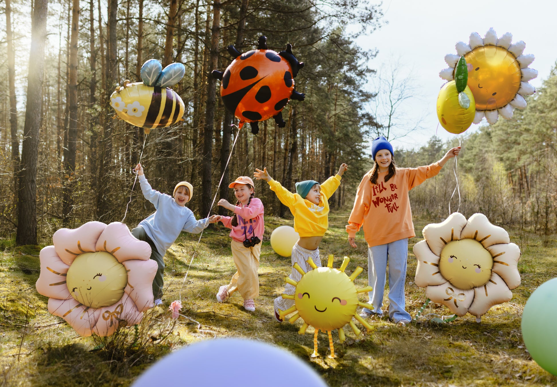 Children playing with balloons shaped like flowers and animals in a forest.