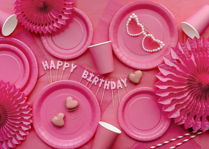 Pink party table setup with plates and decor styled on a dark pink table cover available at our Toronto party shop