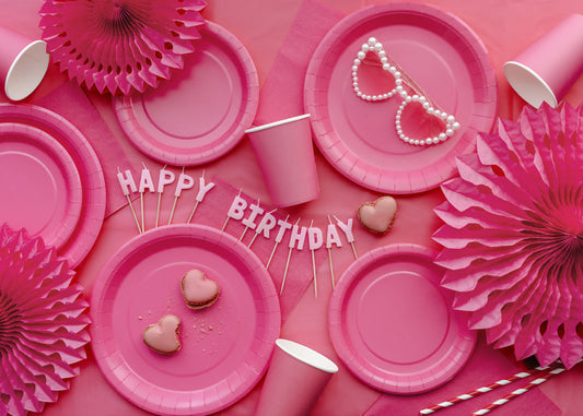 Pink party table setup with plates and decor styled on a dark pink table cover available at our Toronto party shop