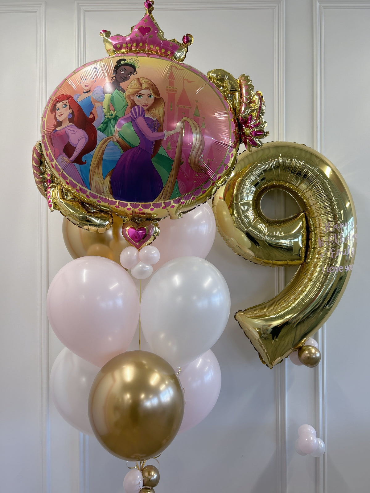 Disney Princess birthday balloon bouquet featuring princess characters, a personalized gold number 9 balloon and pink, white and gold helium balloons in Toronto.