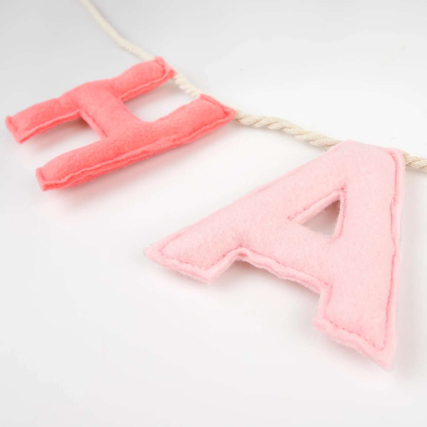  Close-up of soft pink and coral felt letters “H” and “A” on Happy Birthday garland