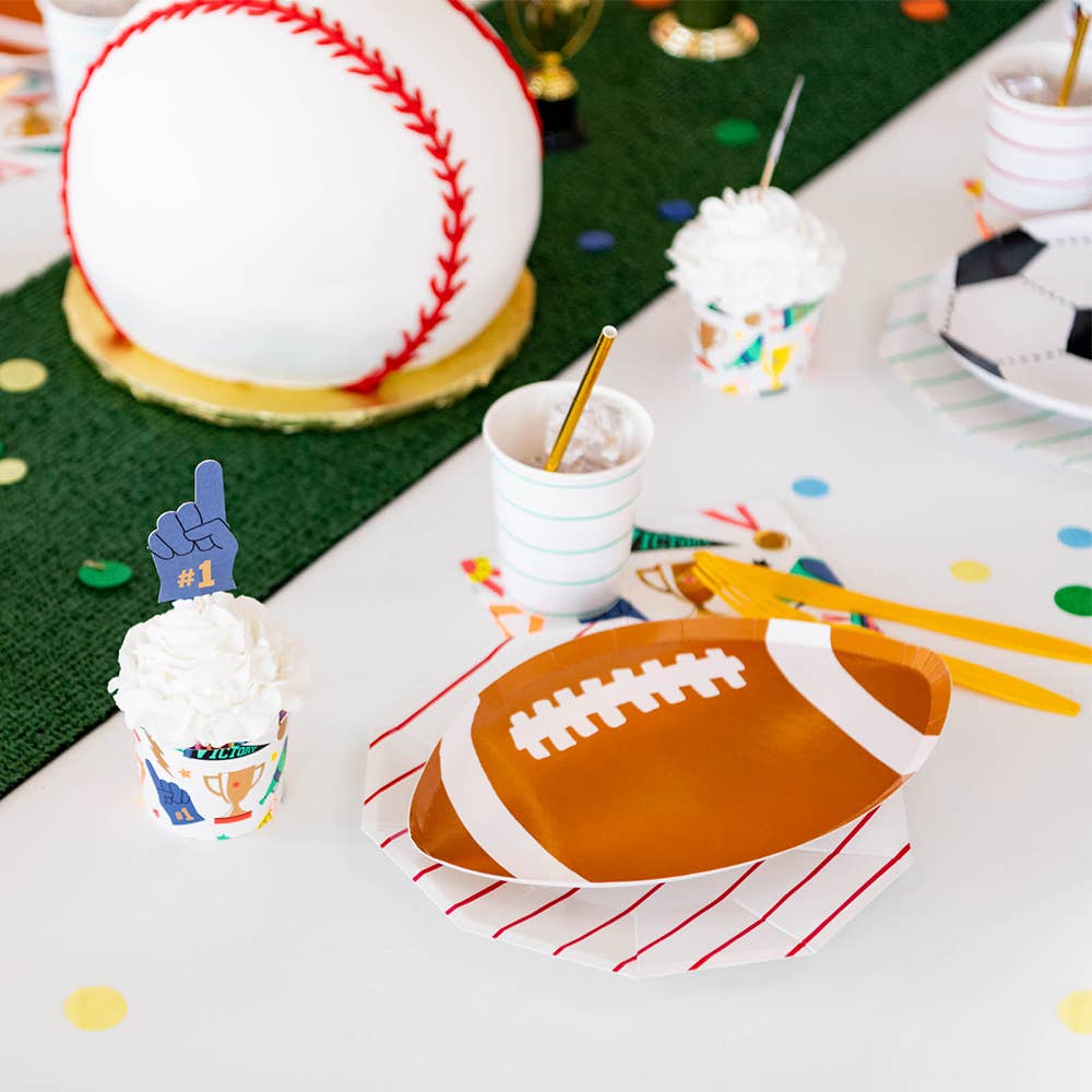 Table setting with sports-themed plates, cups, and decorations including a football plate and baseball ball.