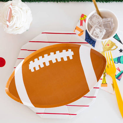 Football-shaped paper plate on a table with decorative elements