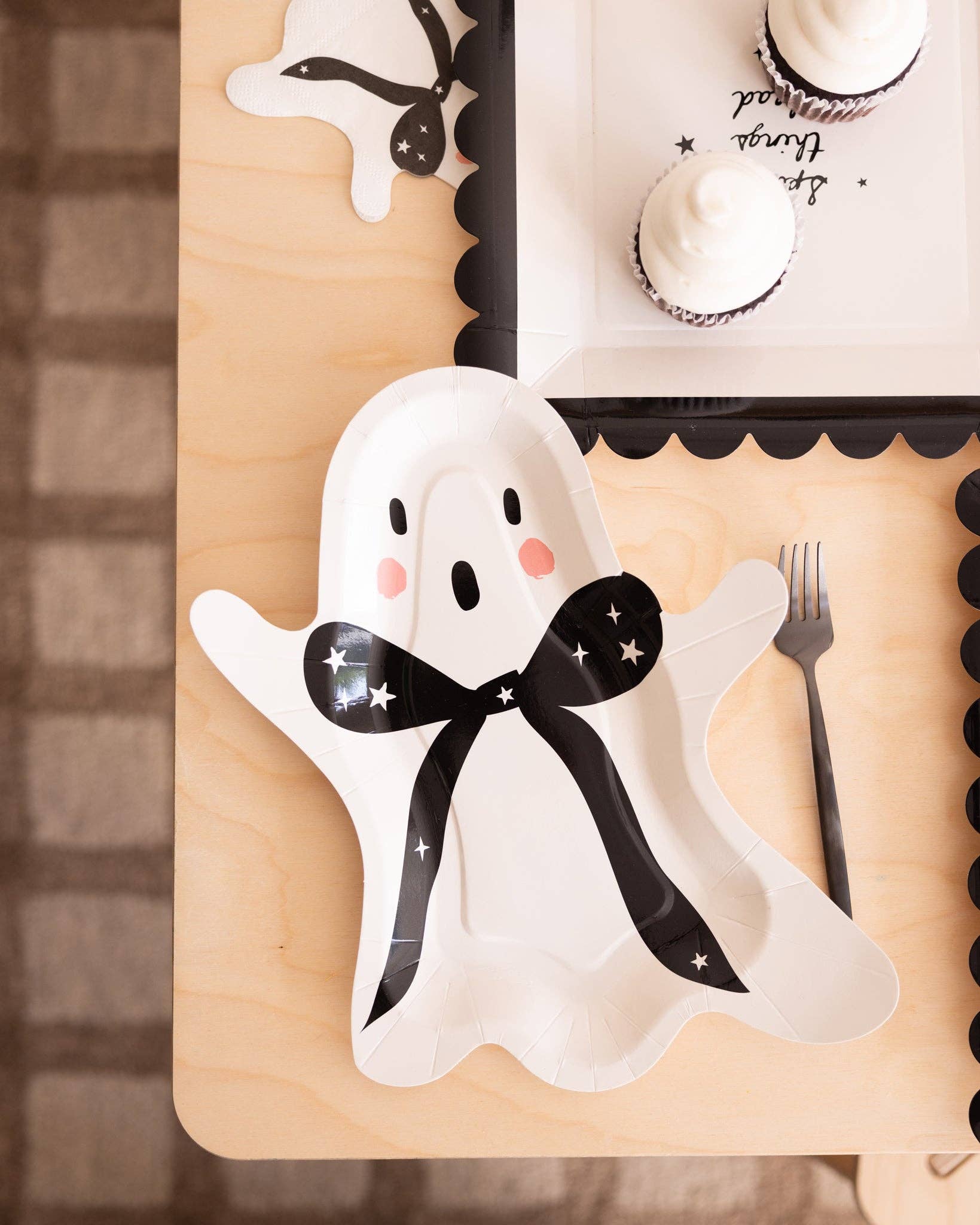 Ghost-shaped plate with a black bow on a wooden surface