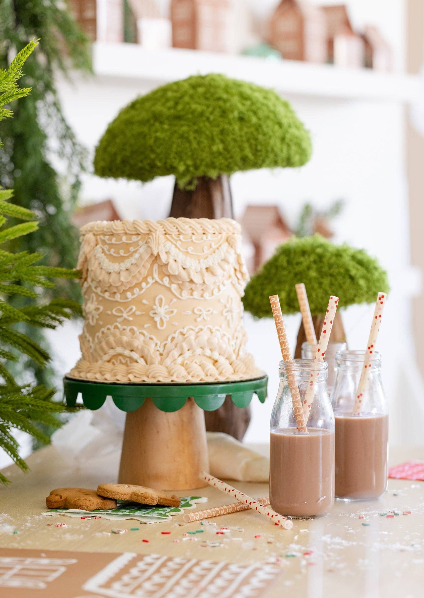 Holiday table with gingerbread straws in glass bottles beside a decorated gingerbread cake, Toronto Christmas party setup.