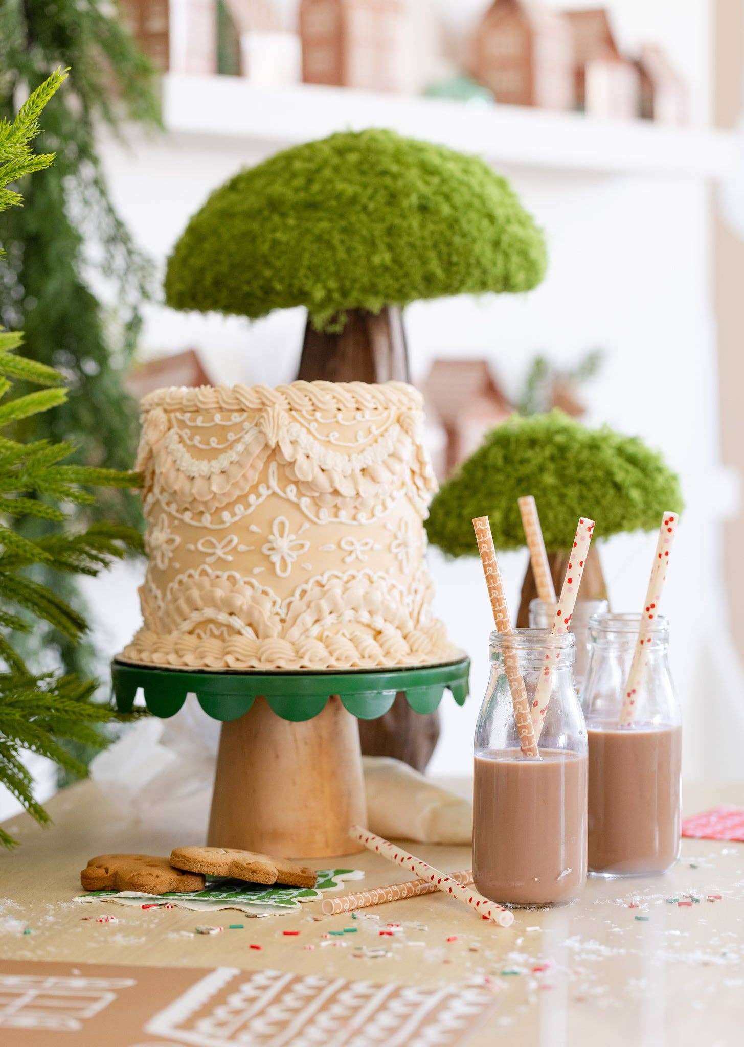 Holiday table with gingerbread straws in glass bottles beside a decorated gingerbread cake, Toronto Christmas party setup.