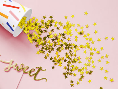 Gold star confetti spilling from a party cup onto a pink table, fun party detail available in Toronto and ships across Canada.