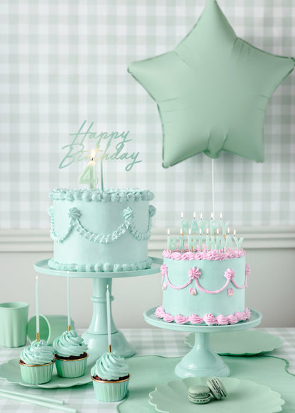 green reusable happy birthday cake topper on a pipped green cake 