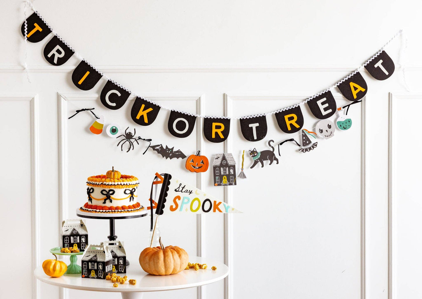 Halloween icons garland styled with a trick or treat banner above a Halloween party table.