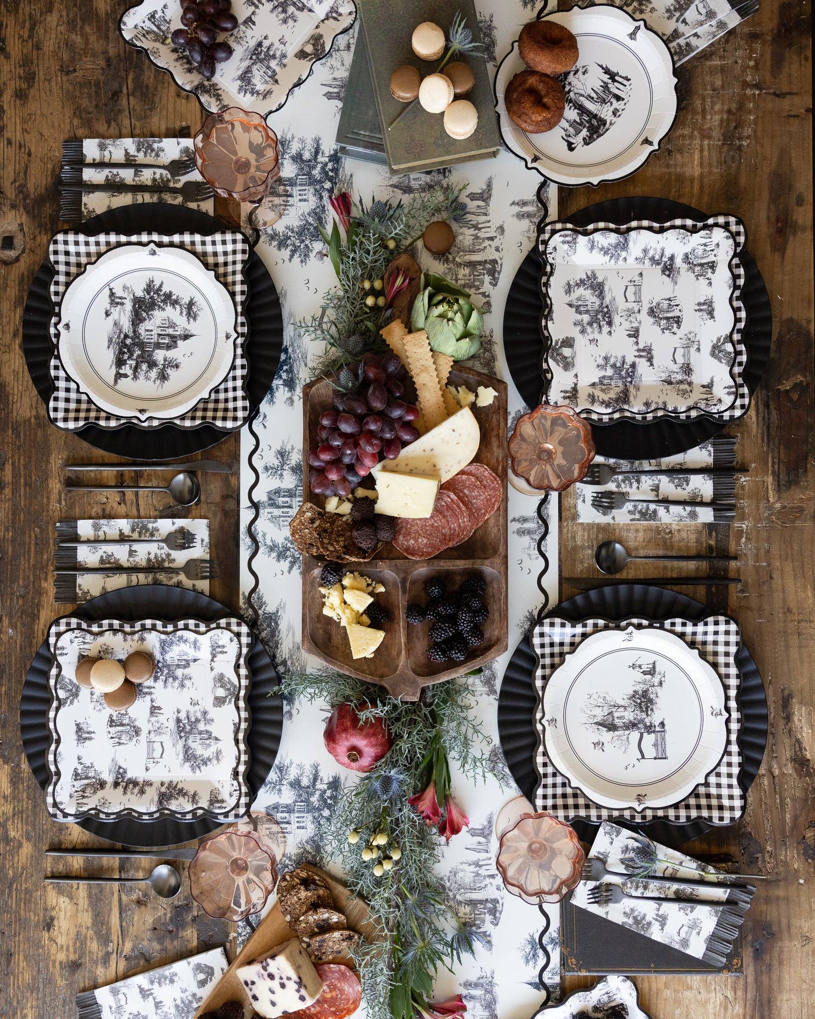 Vintage black and white Halloween party table setting with haunted toile paper plates, napkins and spooky table decor.