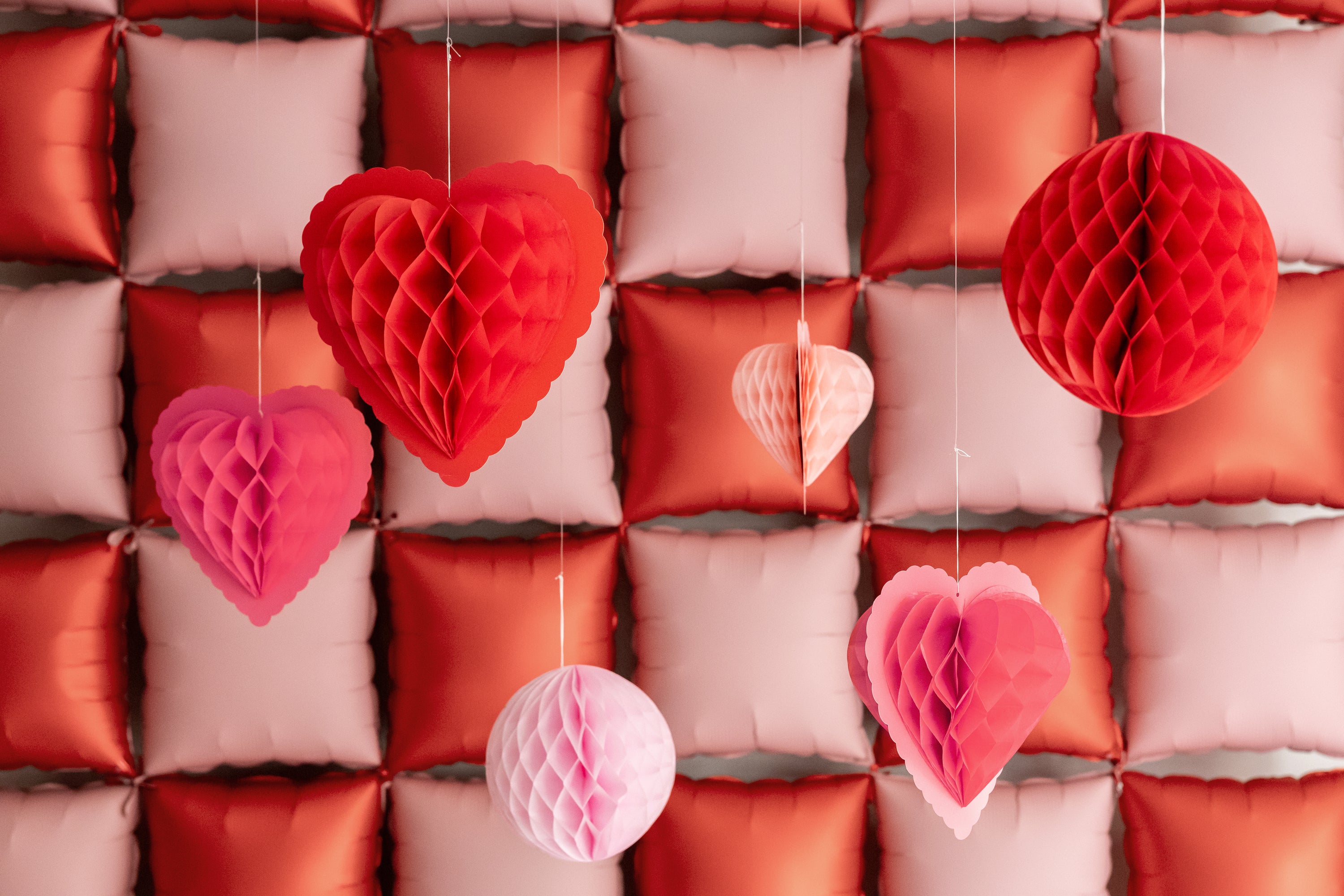 Hanging honeycomb heart decorations styled with a red and pink party backdrop, available in Toronto and shipping across Canada.