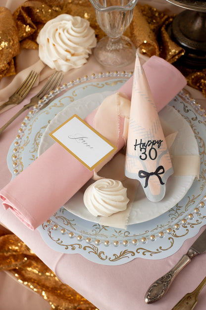 Elegant place setting with Happy 30 scalloped napkin and pink accents, styled for milestone birthday celebrations.