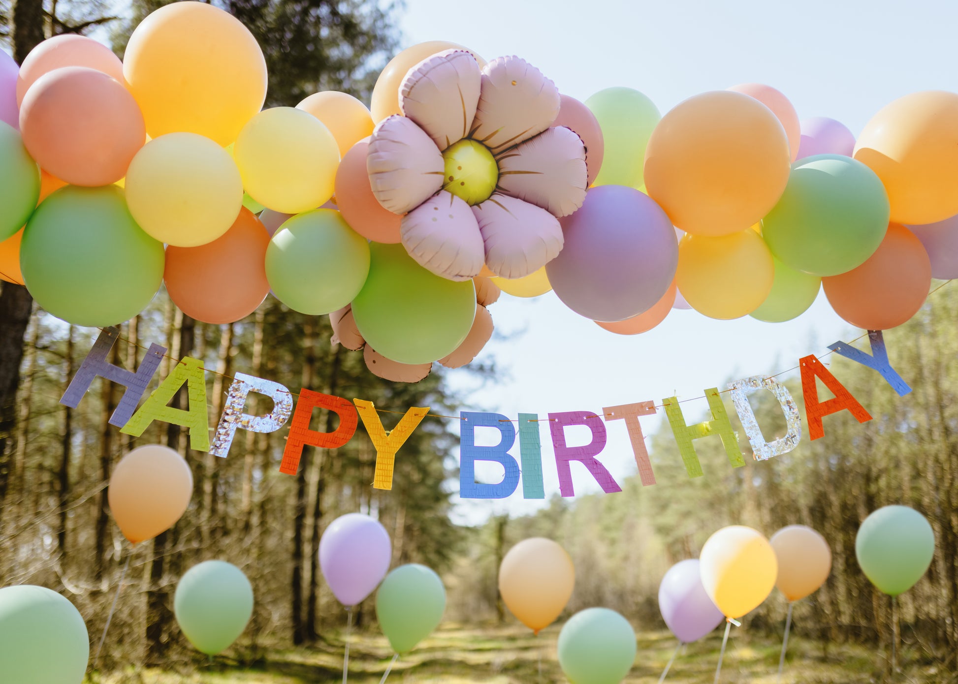 Happy Birthday banner hung under pastel balloon arch, festive décor shipping across Canada.