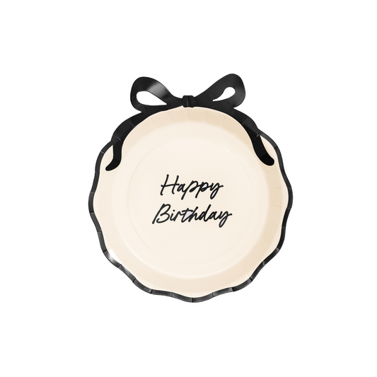 Cream paper plate with scalloped edges, black bow detail, and “Happy Birthday” script.