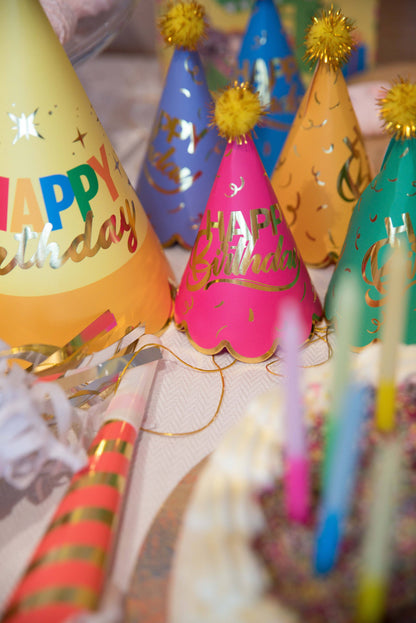 Colorful party hats with 'Happy Birthday' text on a table.