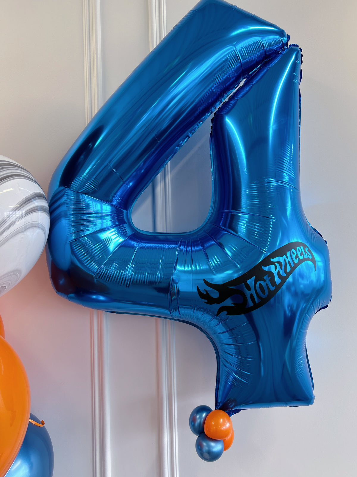 Blue foil number 4 birthday balloon with Hot Wheels-inspired logo and mini balloon detail.