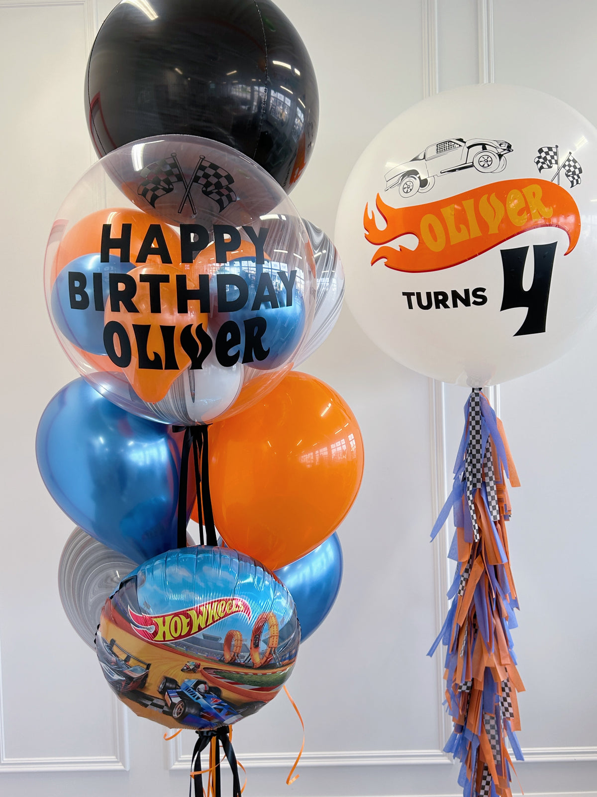 Personalized Hot Wheels birthday balloons with racing-themed bubble balloon, jumbo balloon + blue number balloon.