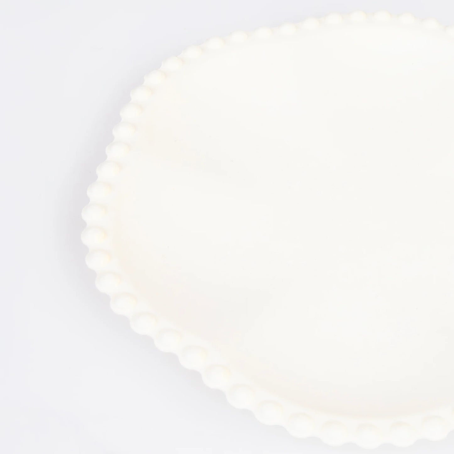 Close-up of ivory scalloped paper plate with beaded edge detail