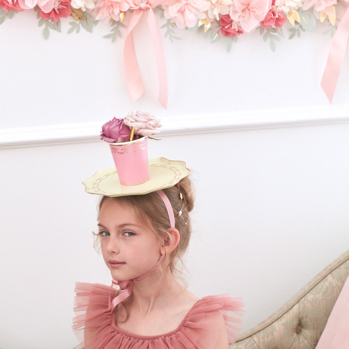 Child wearing playful hat with Ladurée Paris dinner plate by Meri Meri at a floral-themed party, shipping across Canada.