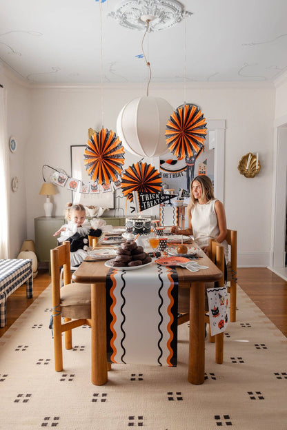 Dining room with Halloween decorations, including paper fans and a tablecloth.