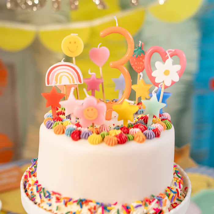 Colourful birthday cake with candles and decorations by meri meri.