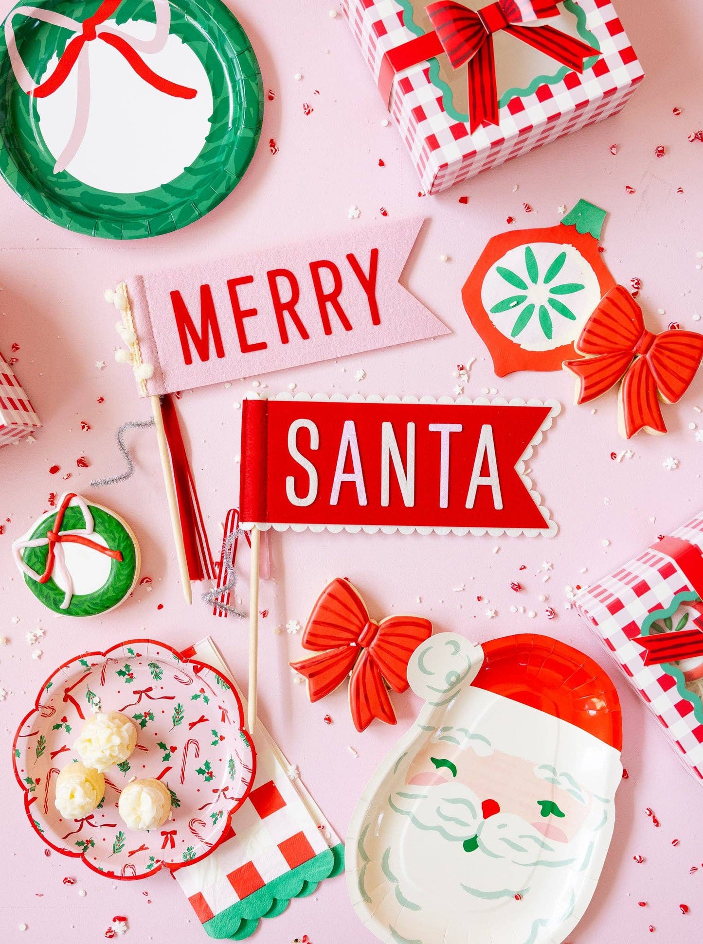 Flat lay with Merry & Santa felt pennants styled with Christmas plates and bows, available at our Toronto party shop