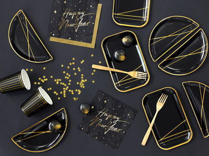 Metallic gold star confetti scattered across black New Year’s Eve table setting with matching plates and cups.