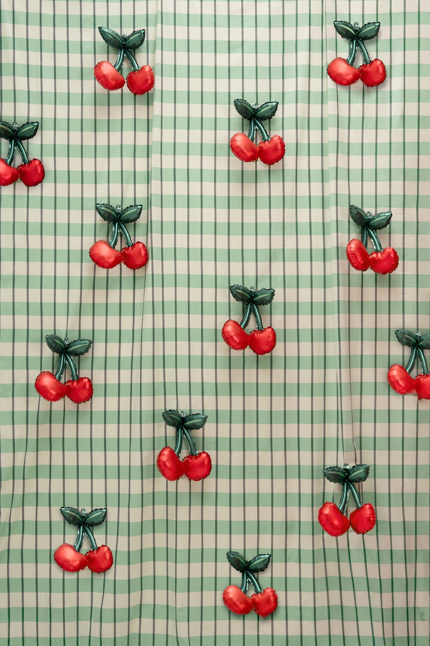 Cherry foil balloon wall backdrop with mini cherry balloons on green gingham, perfect for Toronto parties and photo booths.