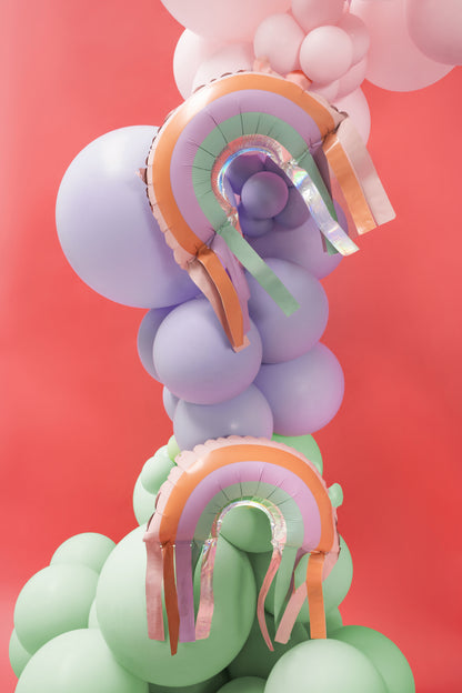 Colorful balloon arch with rainbow decorations against a red background