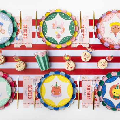 Circus birthday table setting with colourful striped plates, circus animal plates, napkins and gold cutlery
