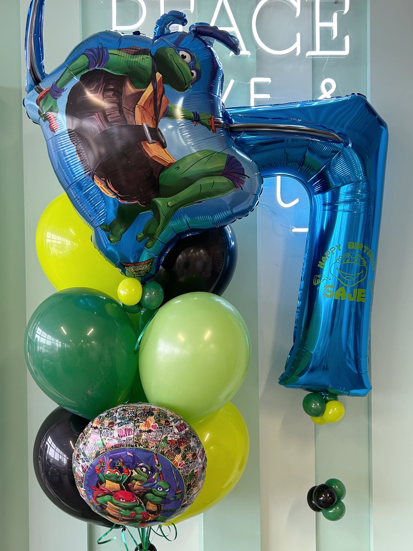 Ninja turtle-themed birthday balloons with character foils, green, lime and black latex balloons and personalized number 7.