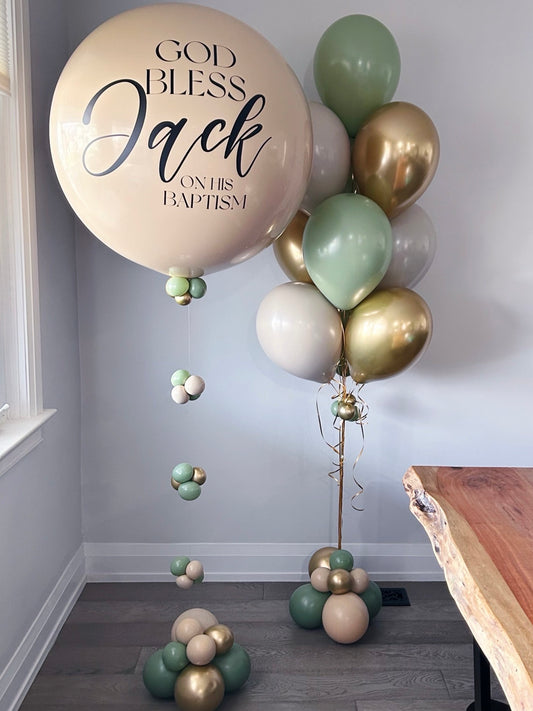 Decorative balloon arrangement with 'God Bless Jack on his Baptism' text in a room.