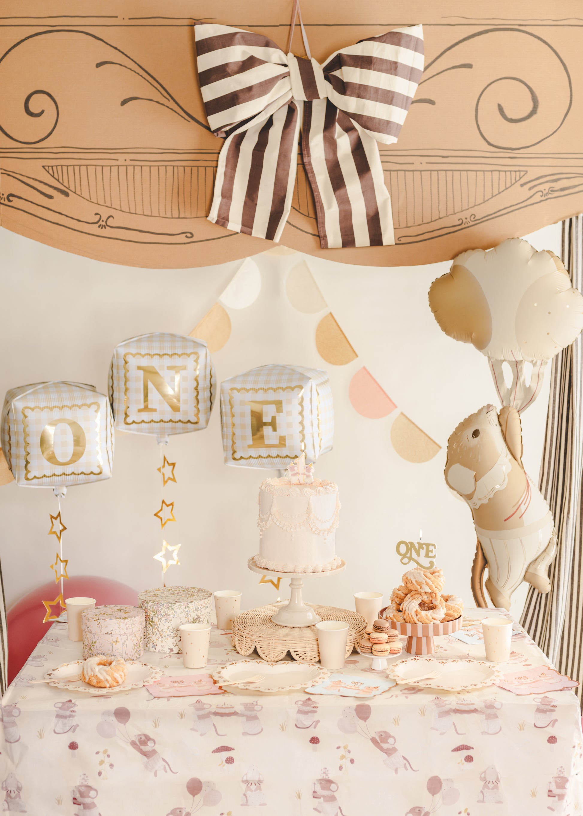 “ONE” cube foil balloons styled above a first birthday cake table with neutral decor, available at our Toronto party shop.