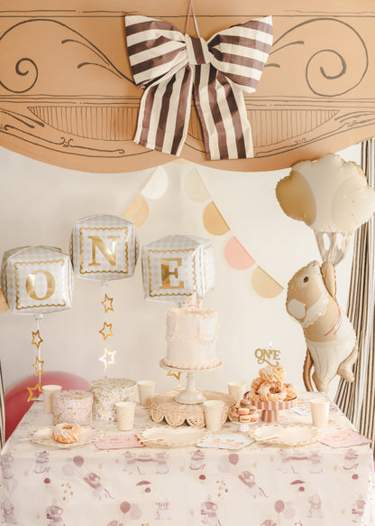 “ONE” cube foil balloons styled above a first birthday cake table with neutral decor, available at our Toronto party shop.