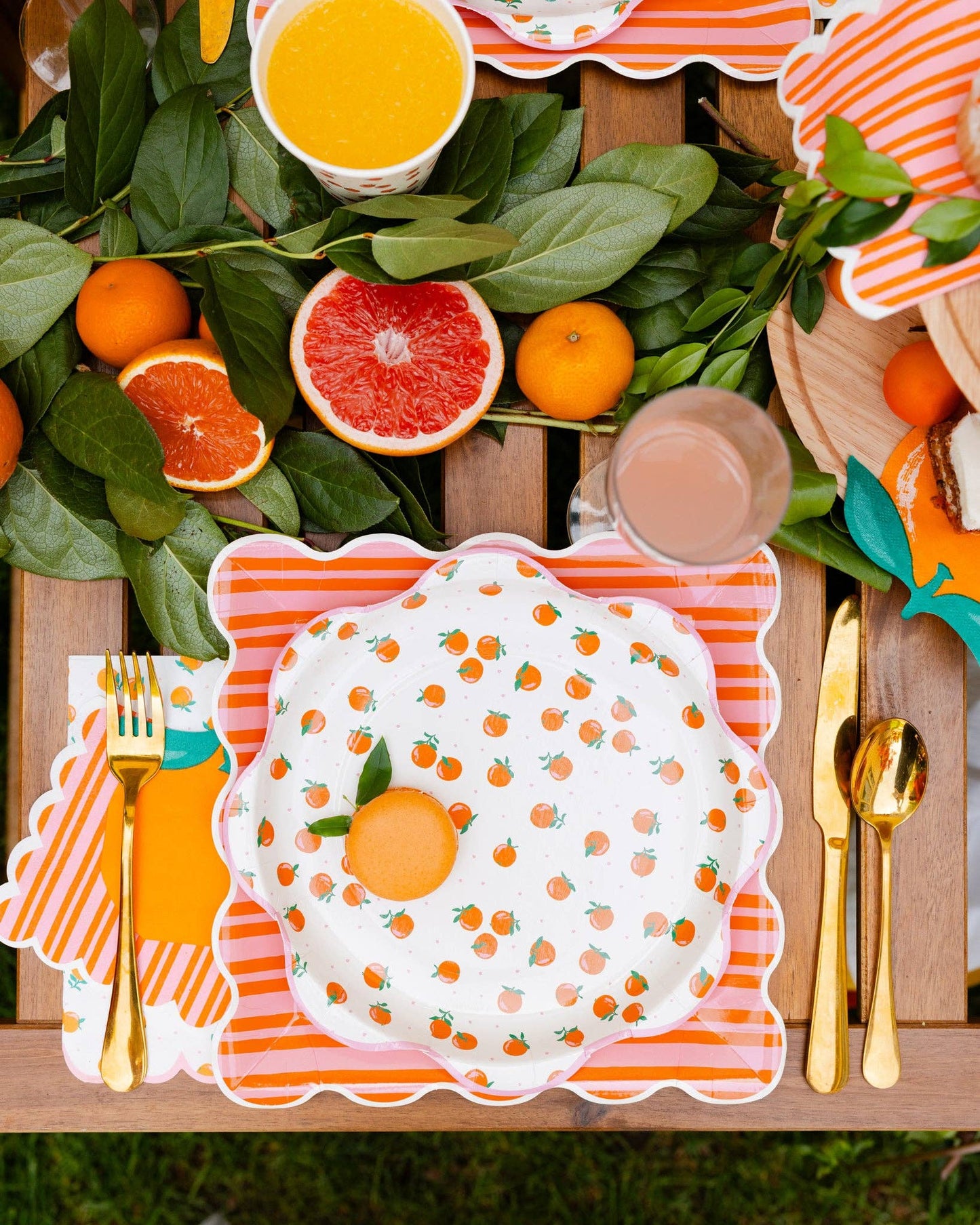Orange and pink striped paper plates layered with citrus party tableware