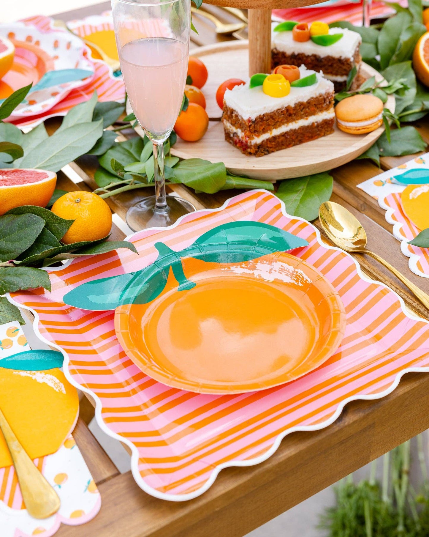 Orange and pink striped scalloped plates styled on a colourful citrus party table