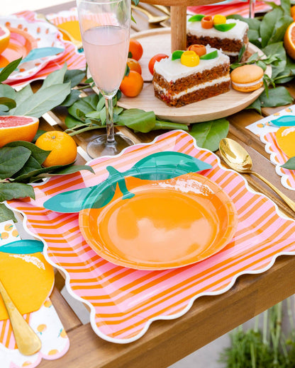 Orange and pink striped scalloped plates styled on a colourful citrus party table