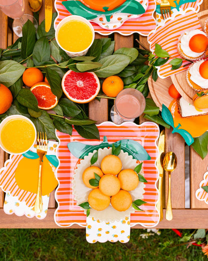 Bright orange fruit table décor featuring patterned napkins and plates, perfect for events across Canada.