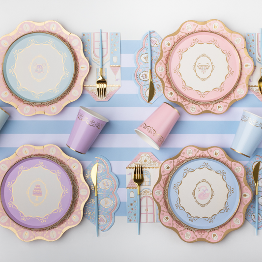 Pastel princess birthday table setting with pink and blue paper plates, cups, napkins and gold cutlery