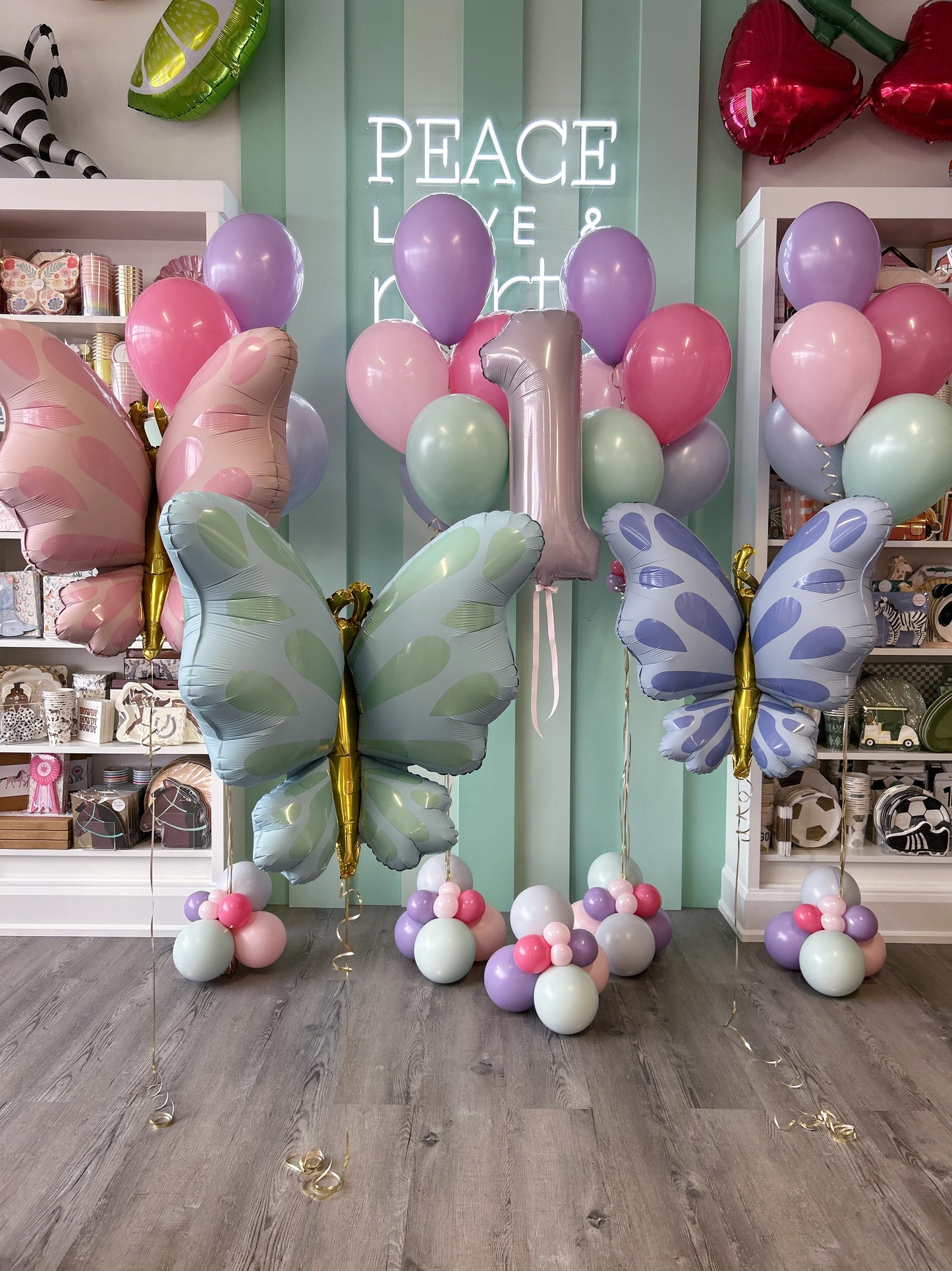 Oversized pastel butterfly balloons in pink, mint and purple with coordinating birthday balloons and a foil number 1.
