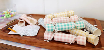 Pastel gingham Easter crackers arranged on a wooden tray with a dice game for a spring party table. Pick up in Toronto + Canada-wide shipping available.