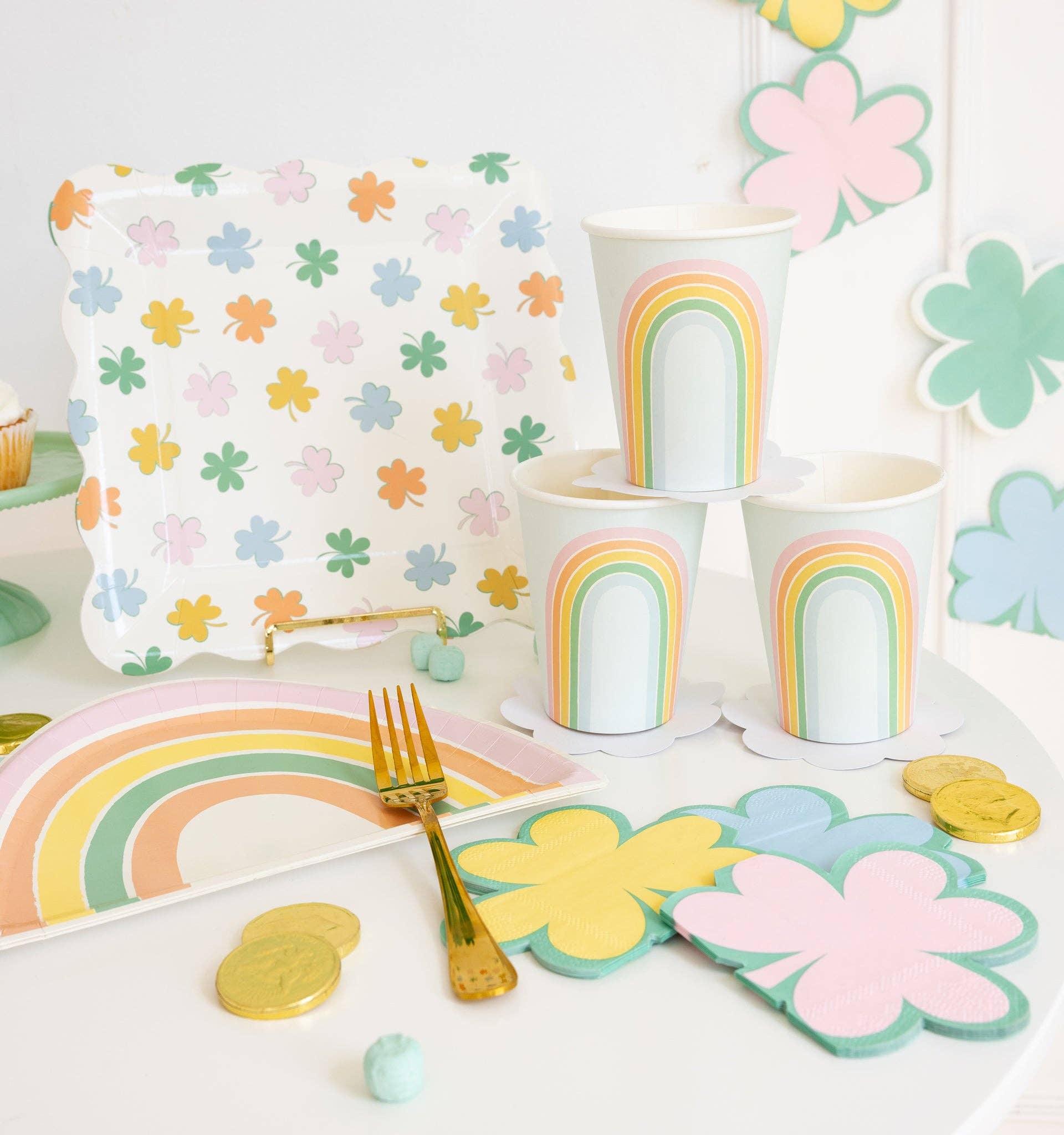 Pastel rainbow shaped plates styled on a party table with matching rainbow cups and spring décor