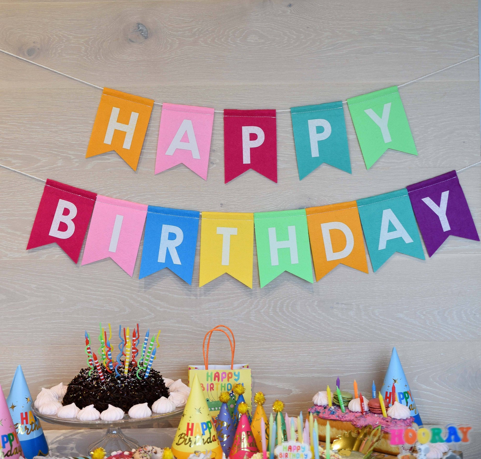 Colorful 'Happy Birthday' banner with birthday cake and decorations on a wooden surface.