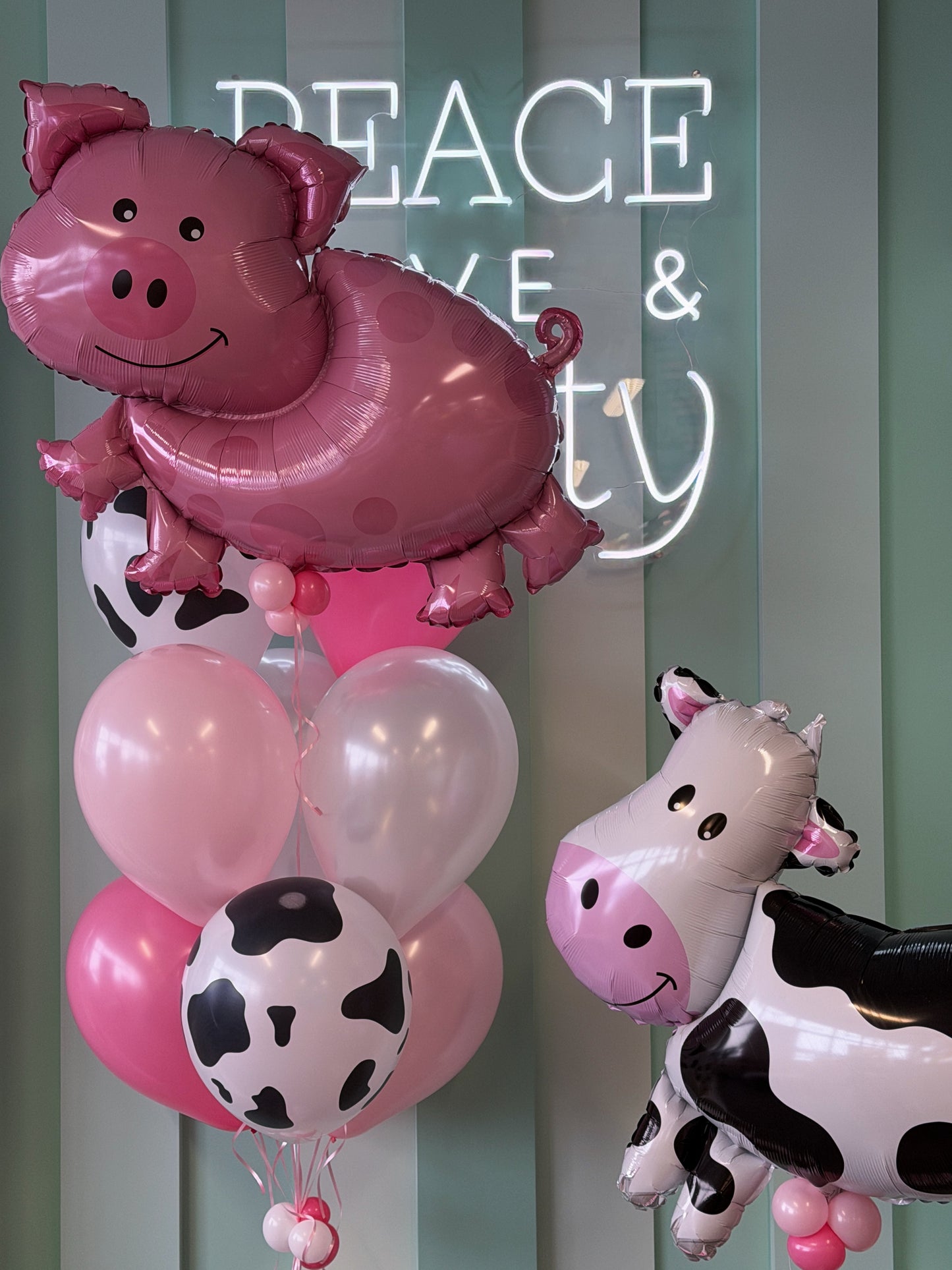 Pink farm birthday balloons featuring oversized pig and cow balloons with pink, white and cow print balloons in Toronto.